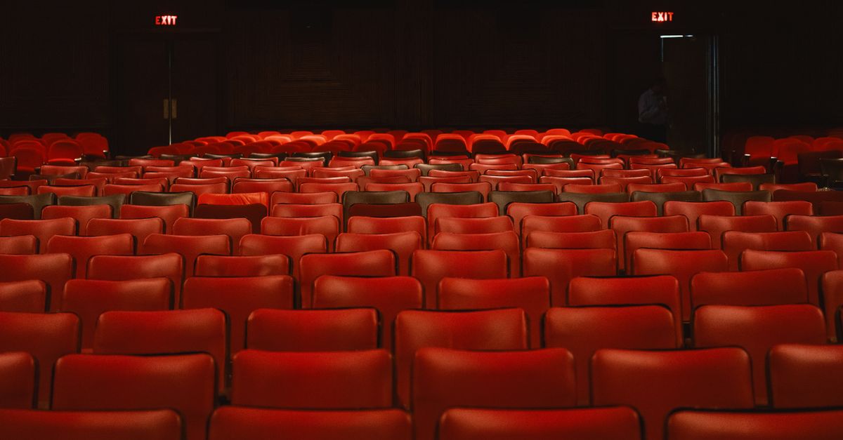 Rows of empty red seats inside a classic movie theater with a vintage ambiance.